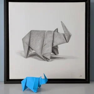 A hyperrealistic drawing with a 3D effect depicting an origami rhinoceros, created by artist Magali Lapeyre-Mirande, on watercolor paper stretched over a stretcher frame and mounted in a shadow box