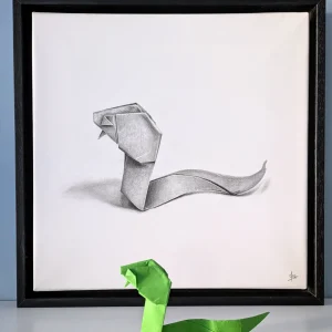 A hyperrealistic drawing with a 3D effect depicting an origami snake, created by artist Magali Lapeyre-Mirande, on watercolor paper stretched over a stretcher frame and mounted in a shadow box
